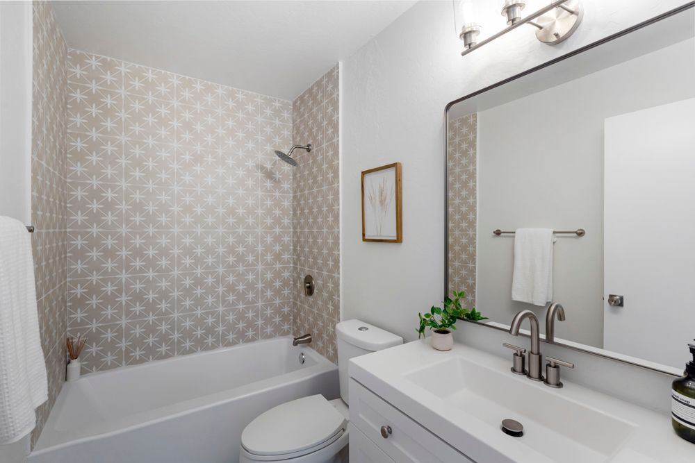 Updated hallway bath with modern vanity and starburst tile flooring, presented by Rumana Jabeen Real Estate.