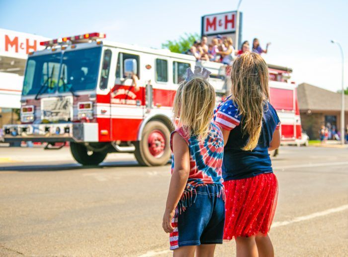 Two little girls are standing in front of a fire truck.