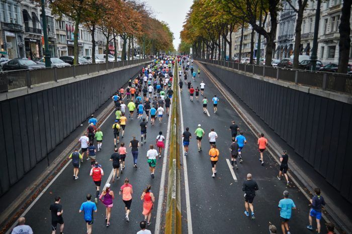 A large group of people are running a marathon on a city street.