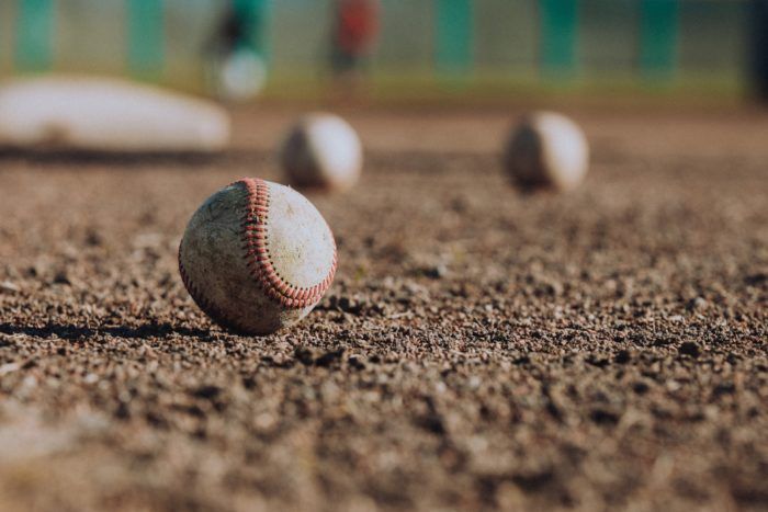 A baseball is sitting on the ground on a baseball field.
