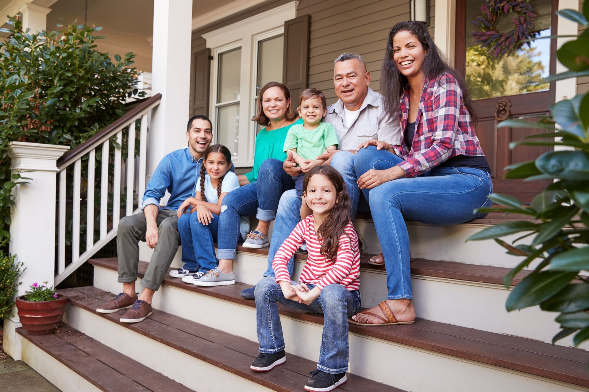 A family is sitting on the steps of their house.