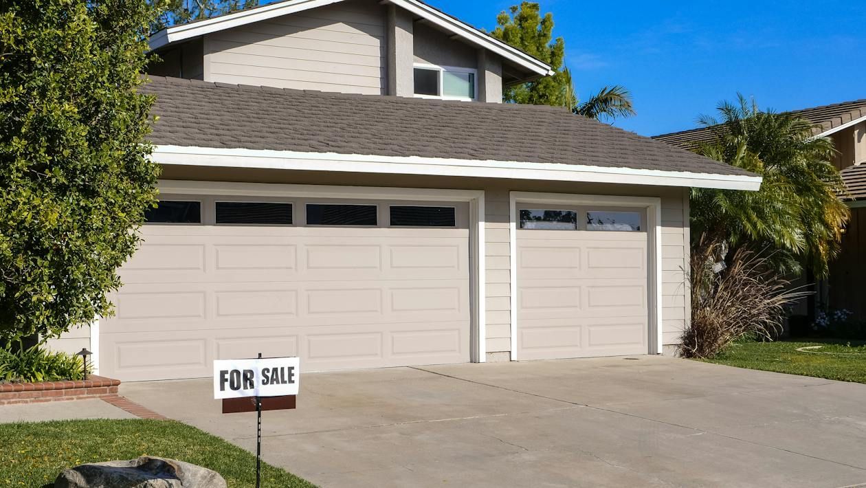 A house with a for sale sign in front of it.