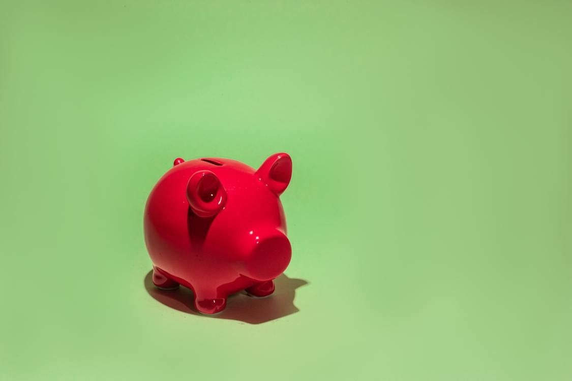 A red piggy bank is sitting on a green surface.