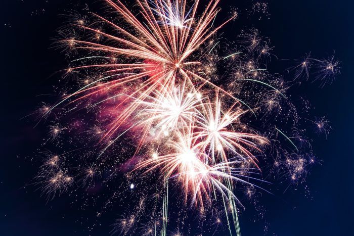 A bunch of fireworks are exploding in the night sky.