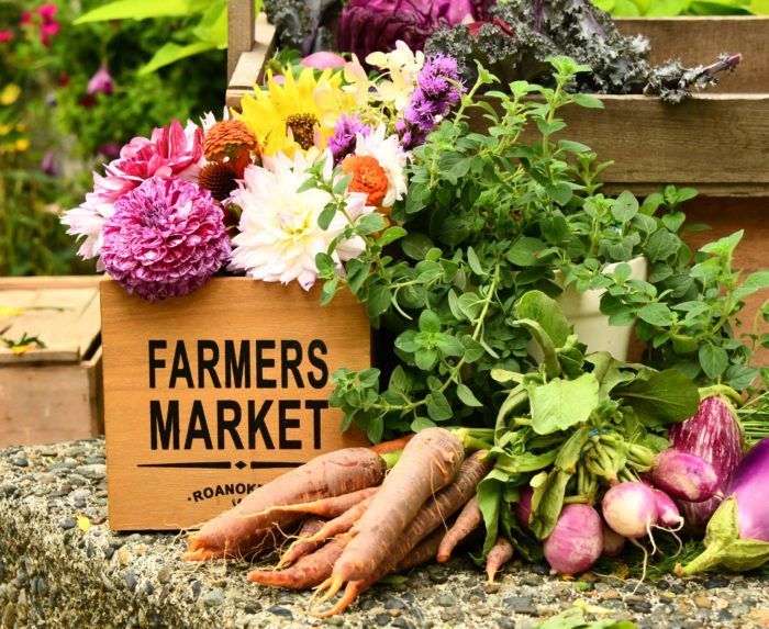 A farmers market sign with carrots and flowers in it