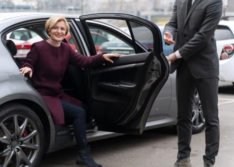 Hombre vestido de negocios mirando por la ventanilla del coche en un aeropuerto.