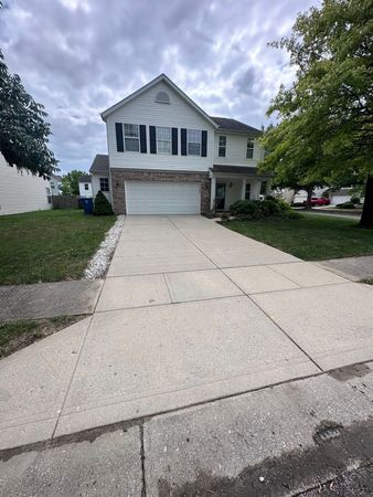 Suburban two-story house with a double garage and wide driveway under a cloudy sky