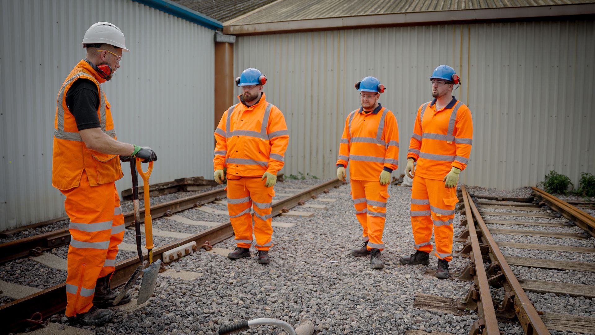 a group of construction workers are standing on train tracks .