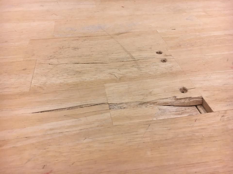 A close up of a piece of wood on a squash court with a hole in it.