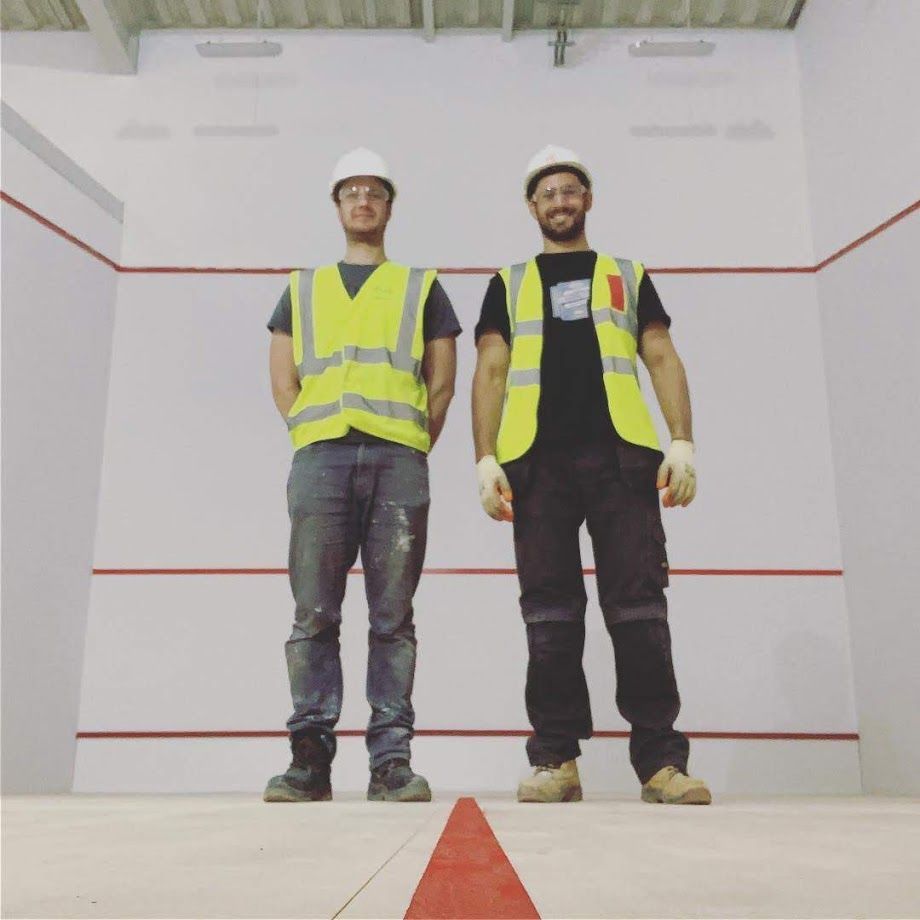 Two men wearing hard hats and safety vests stand next to each other