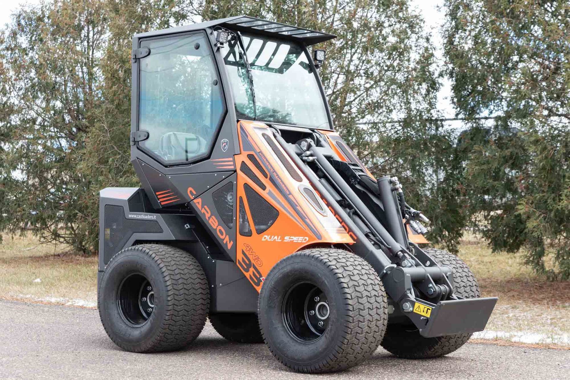 A black and orange tractor is parked on the side of the road.