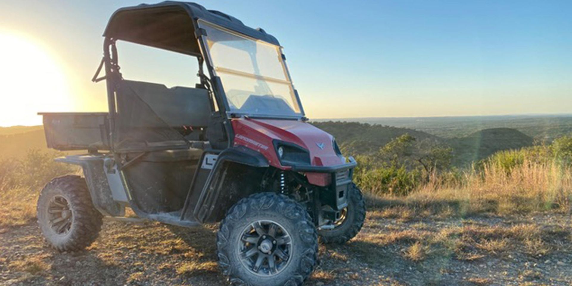 A red atv is parked on top of a hill.