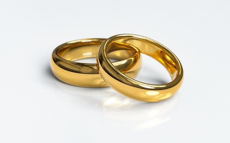 Two shiny gold wedding bands resting against each other on a plain white background.