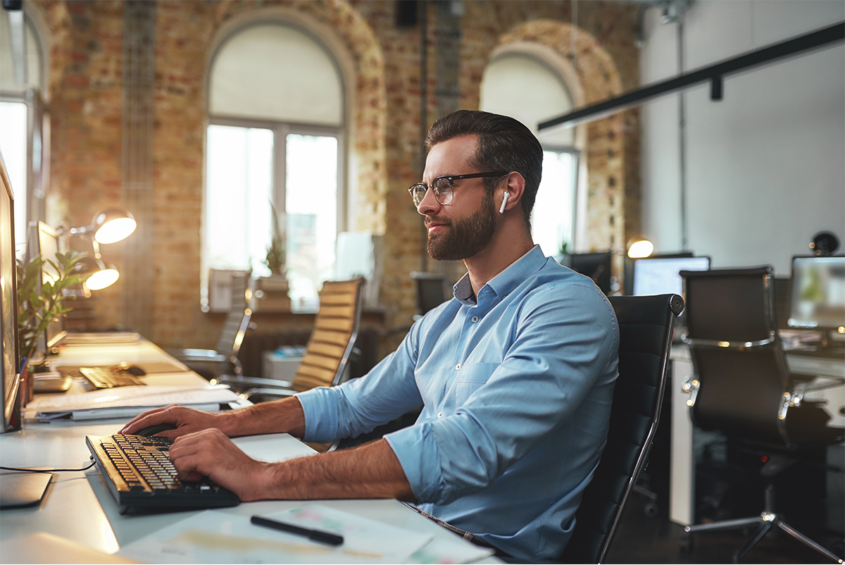 A man is sitting at a desk in front of a computer.