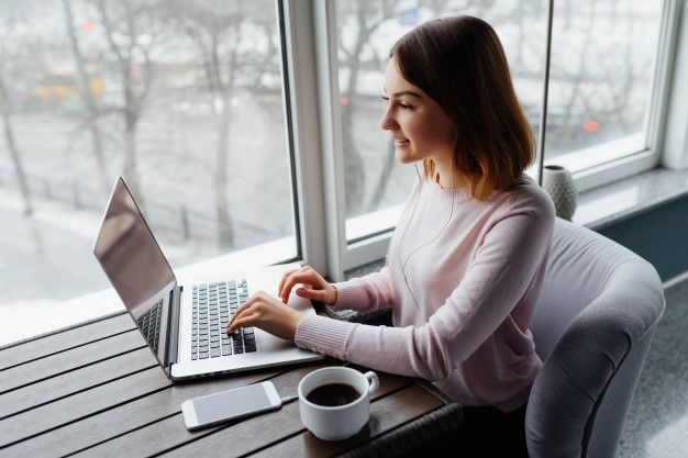 A woman is sitting at a table using a laptop computer.