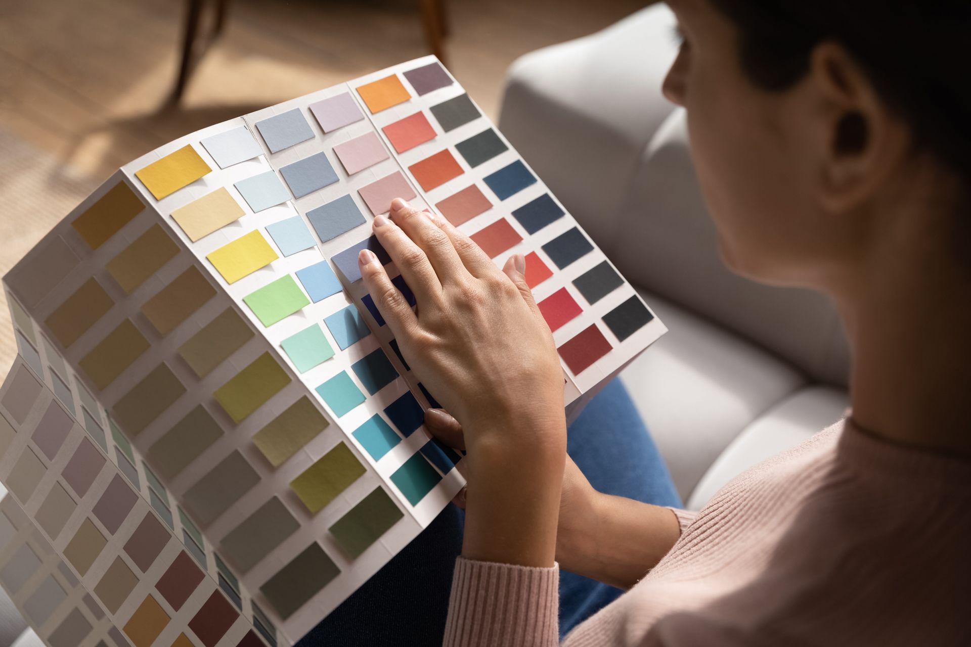 A woman is sitting on a couch looking at a color palette.