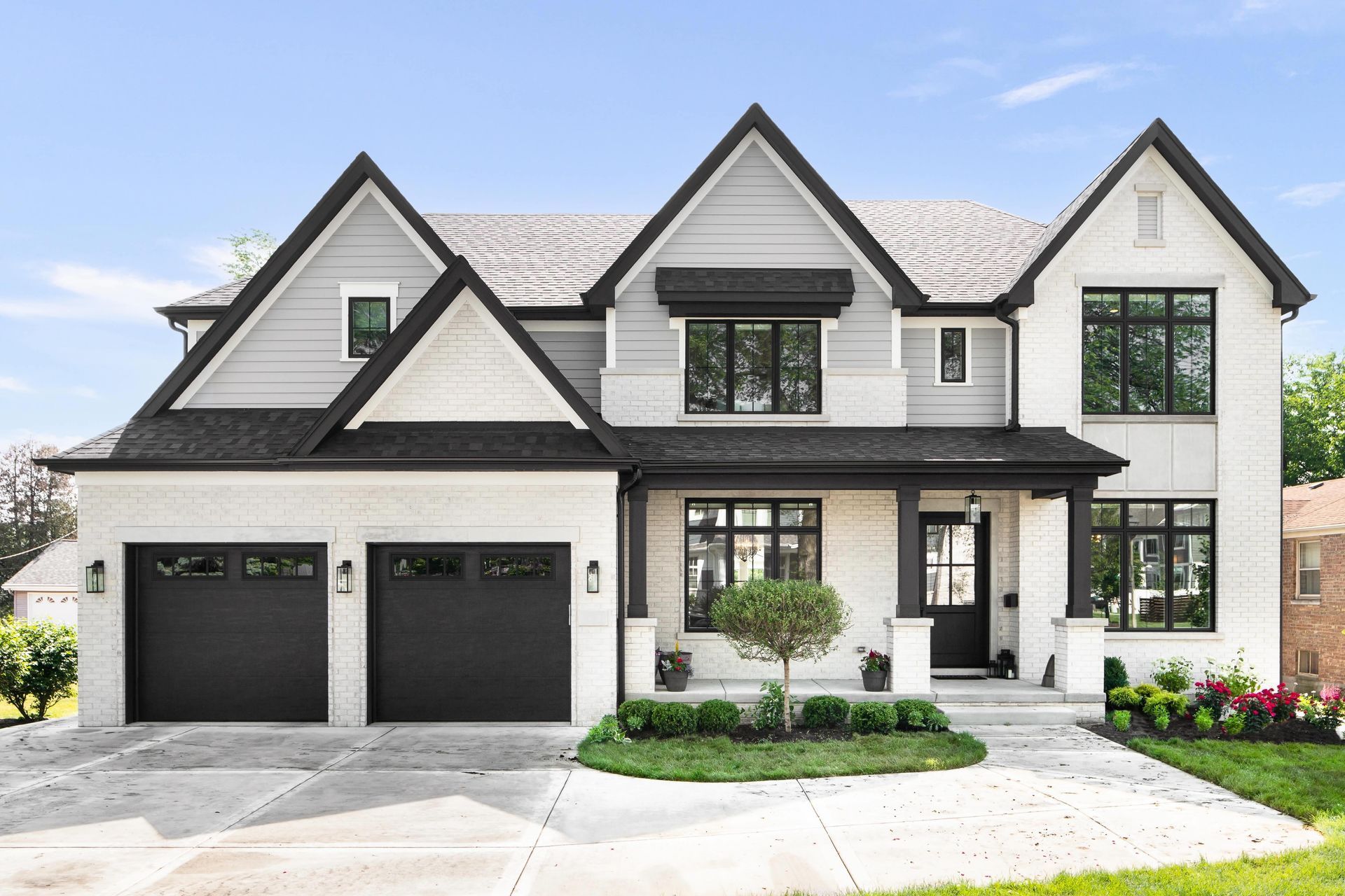 A large white house with black trim and black garage doors.