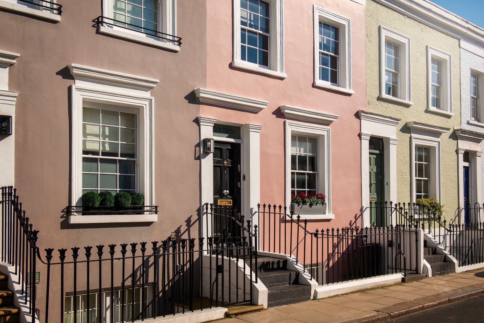 A row of houses with a wrought iron fence on the side of the road.