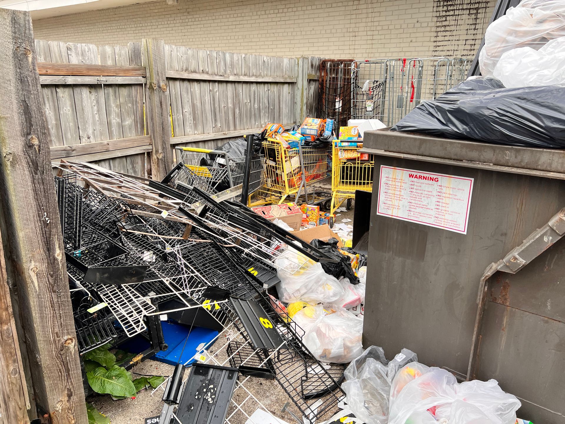 A pile of trash is sitting on top of a dumpster.
