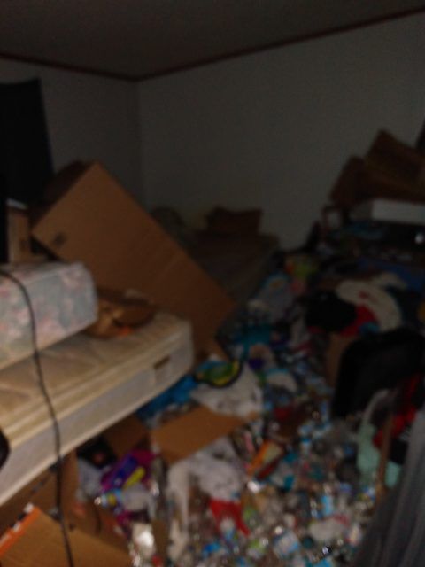 A messy room with a mattress and boxes on the floor.