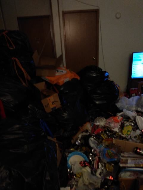 A living room filled with lots of garbage and a television.