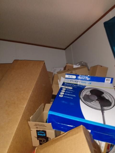 A box of a fan sits on top of a pile of cardboard boxes