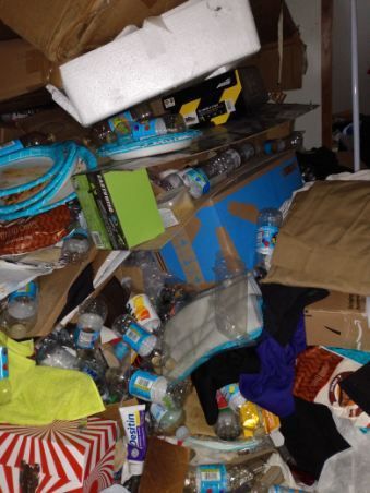 A messy room with a bottle of scotch wipes on the floor