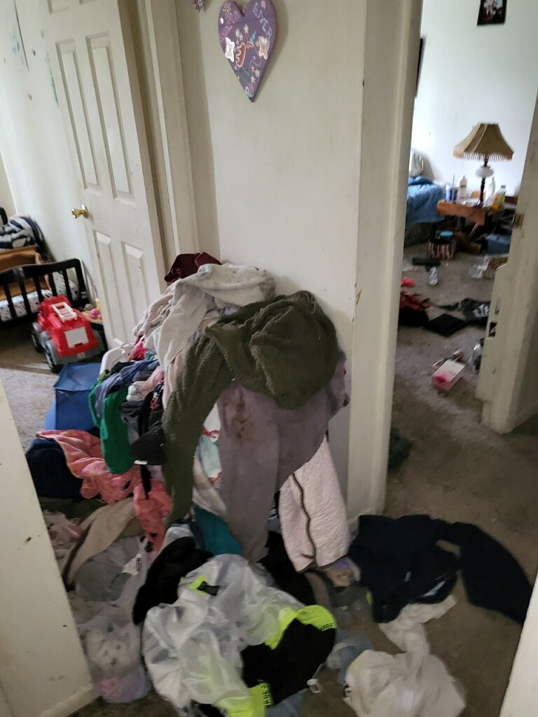 A messy room with a lot of clothes on the floor.
