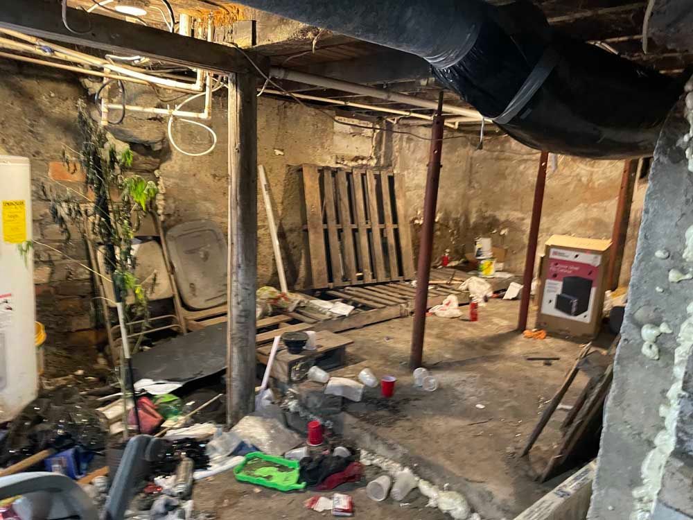 A basement filled with lots of trash and a refrigerator.