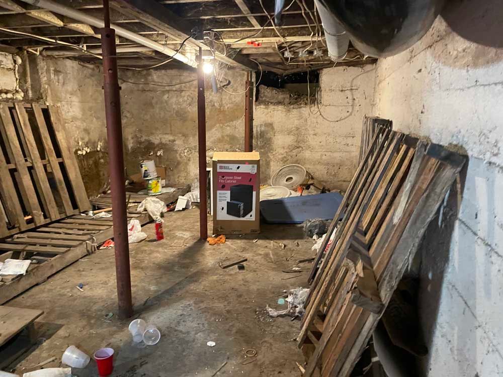 A messy basement with wooden pallets and a box on the floor.