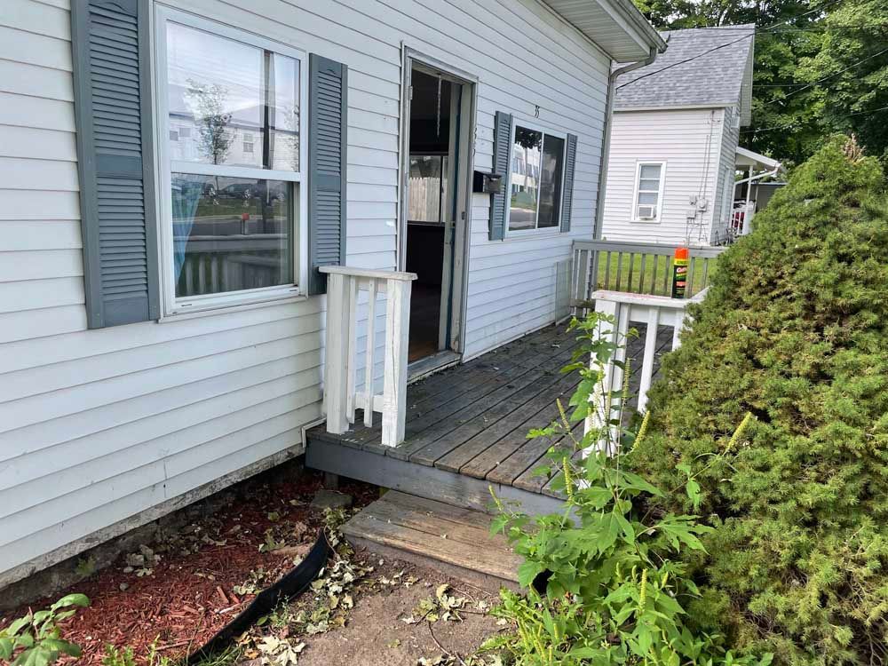 A small white house with a wooden porch and shutters.