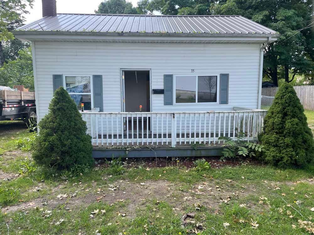 A small white house with a metal roof and a porch.