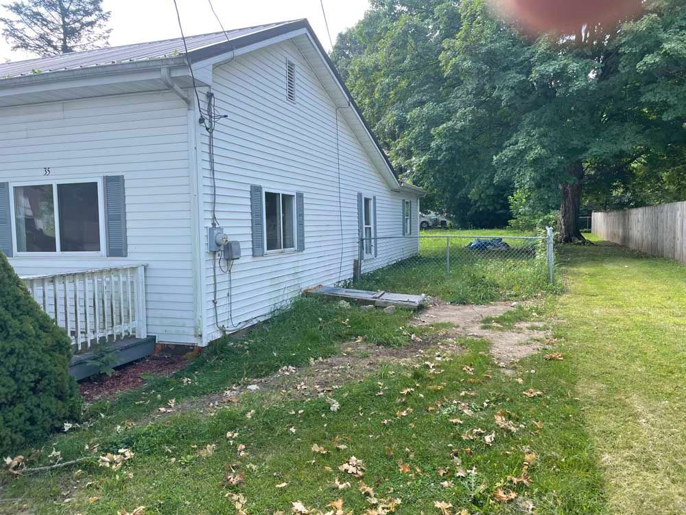 A white house is sitting in the middle of a lush green field.