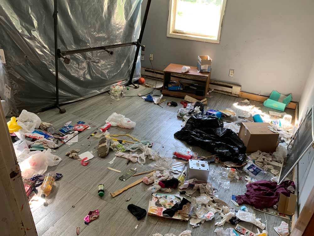 A messy room with a lot of trash on the floor.