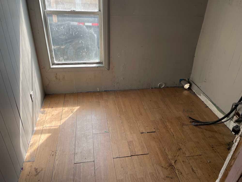 A small room with a wooden floor and a window.