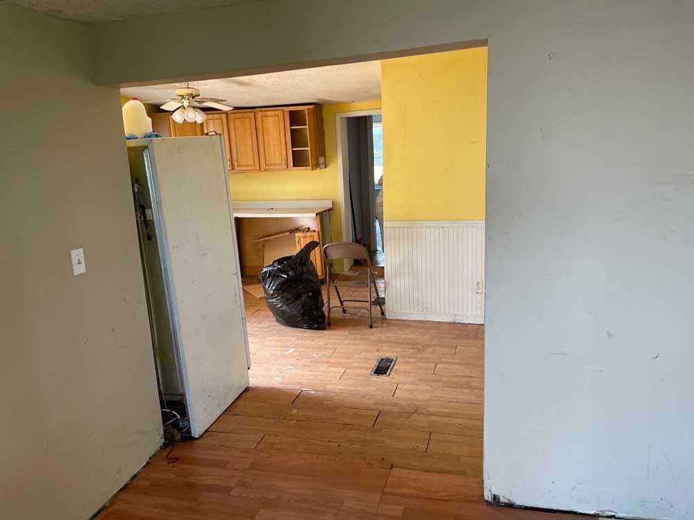 An empty room with a chair and a trash bag in it.