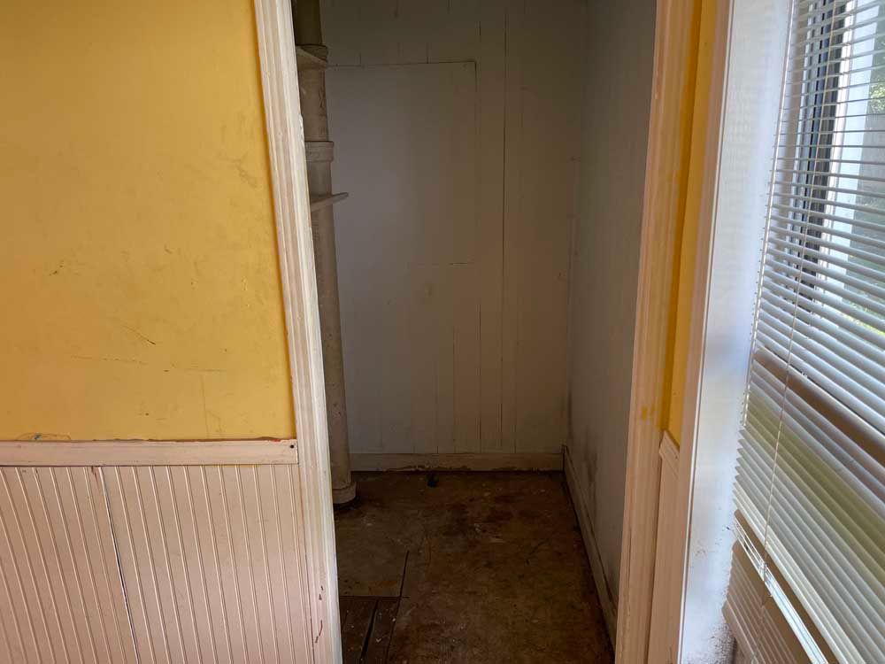 An empty room with a window and blinds in it.