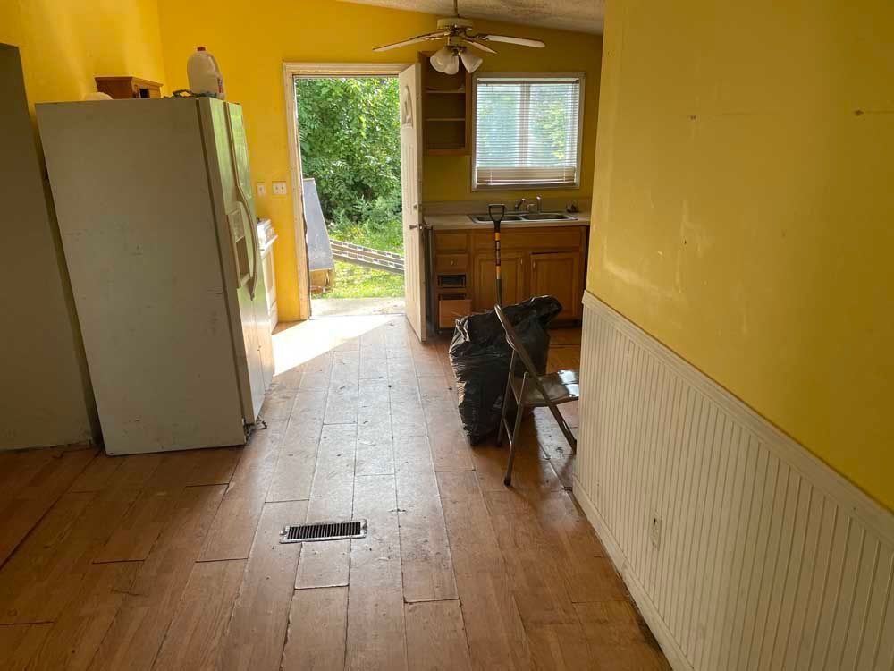 A kitchen with a refrigerator and a ladder in it.