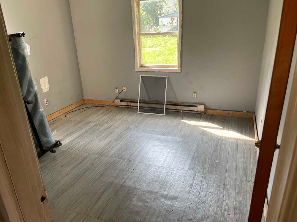 An empty room with a wooden floor and a window.