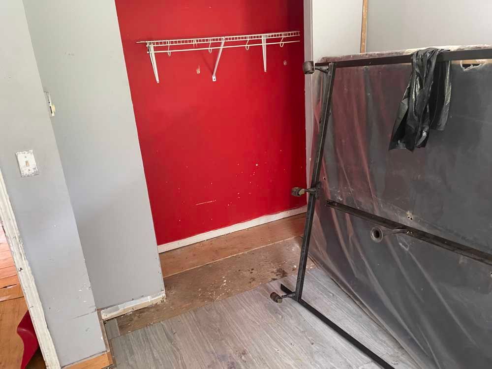 A room with a red wall and a black bag on the floor.