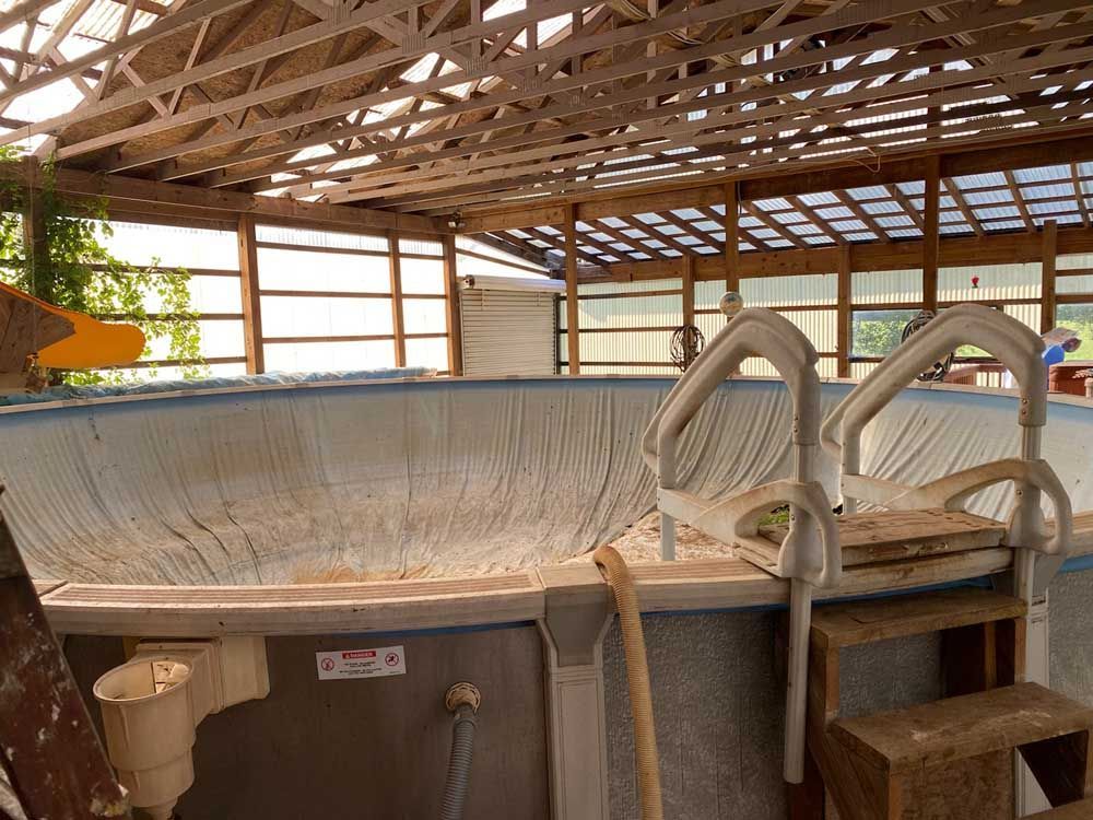 An empty swimming pool with stairs in a barn.