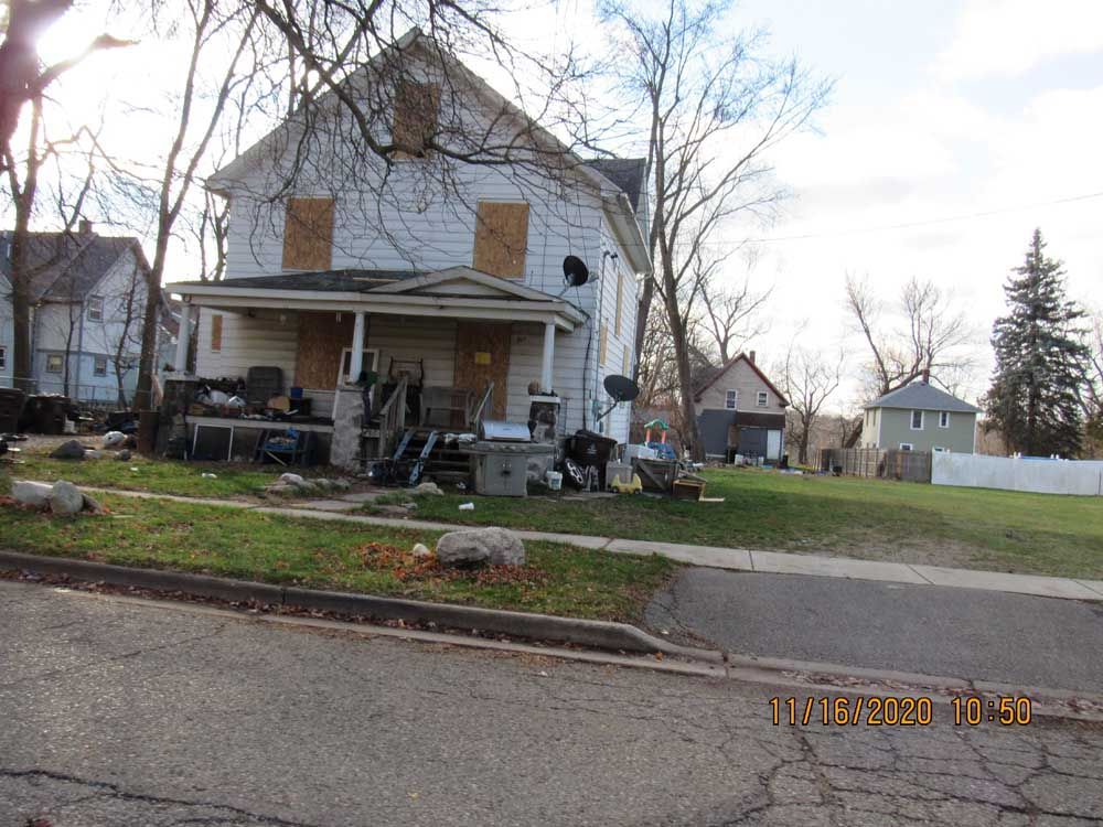 A white house with a porch and a lot of trash in front of it