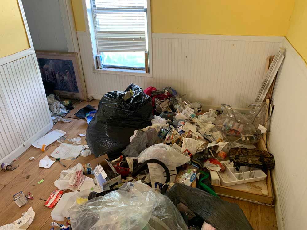 A room with a lot of trash on the floor and a window.