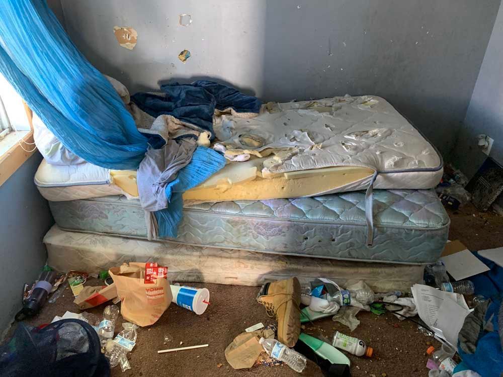 Two mattresses are stacked on top of each other in a messy room.