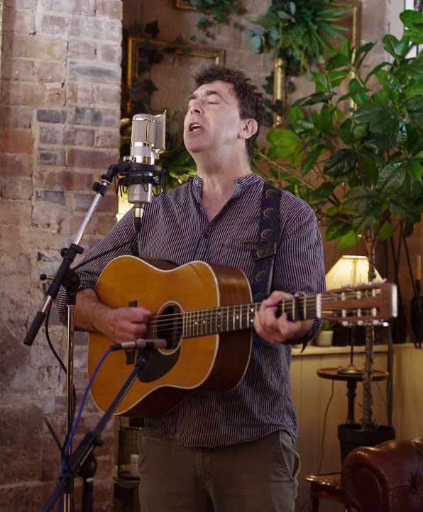 A man is singing into a microphone while playing an acoustic guitar