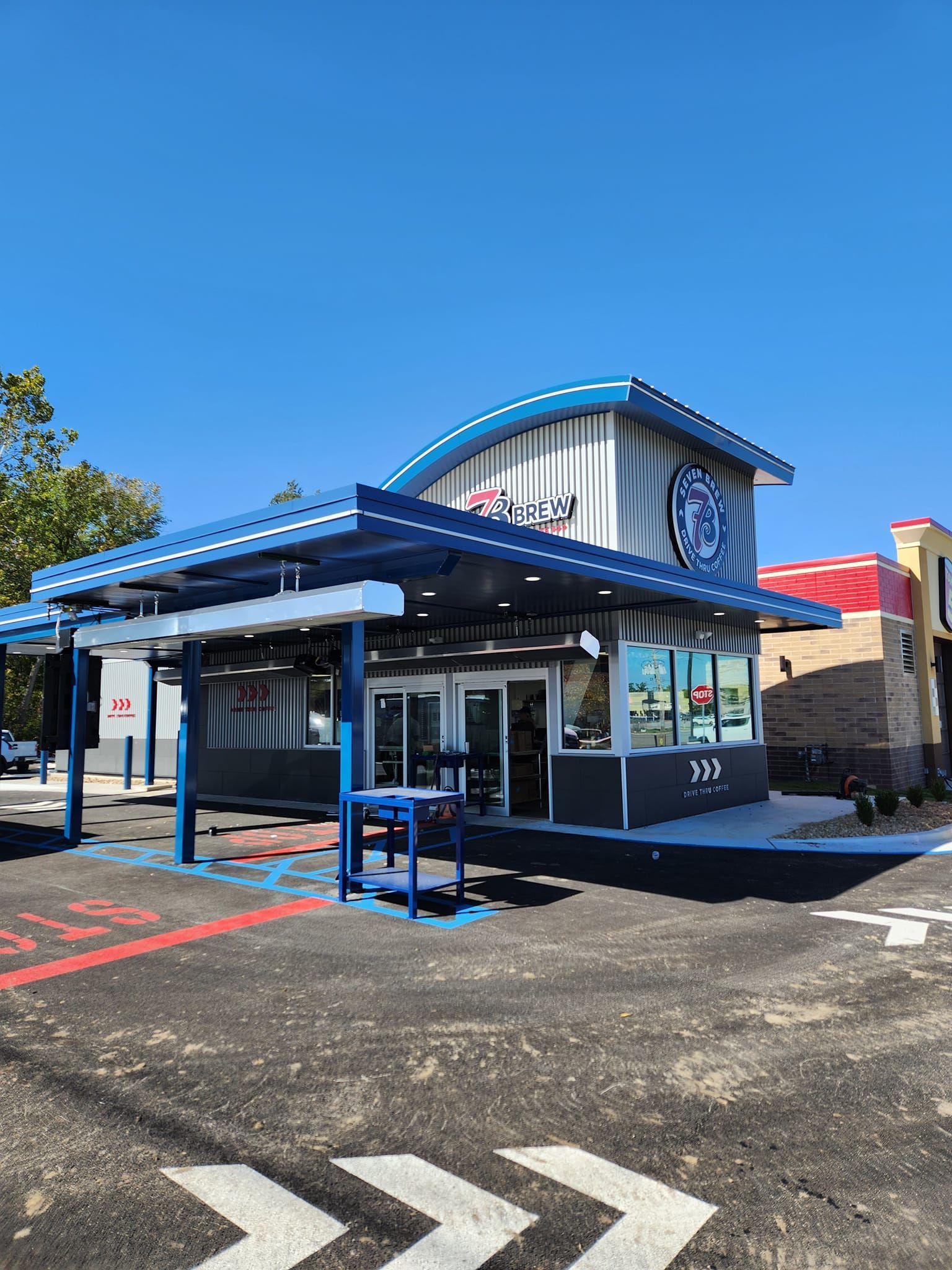 A Fast Food Restaurant with a Blue Awning and a Parking Lot in Front of It .