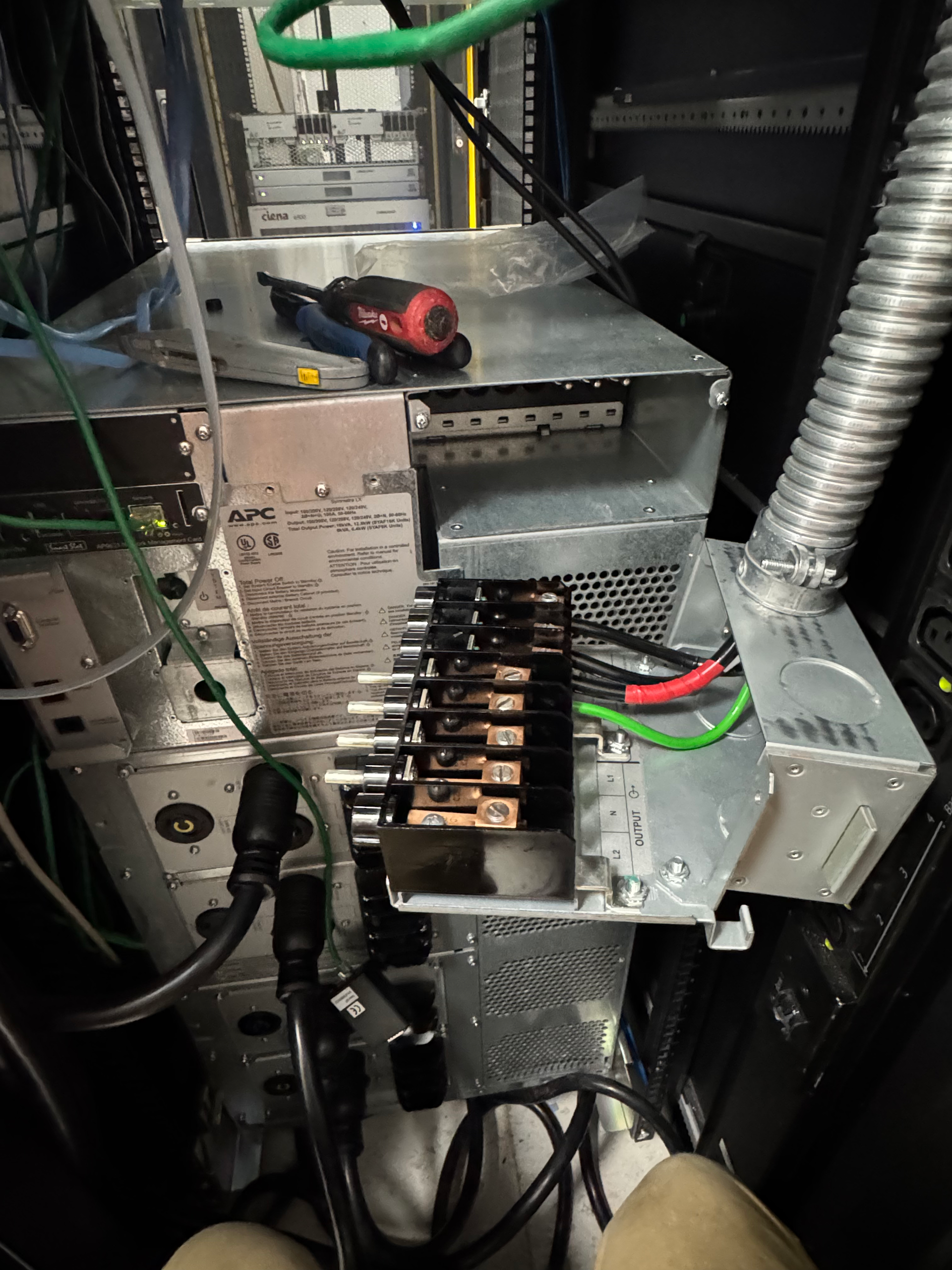 Open electrical cabinet with wiring, relays, and a screwdriver on top of a metal panel.