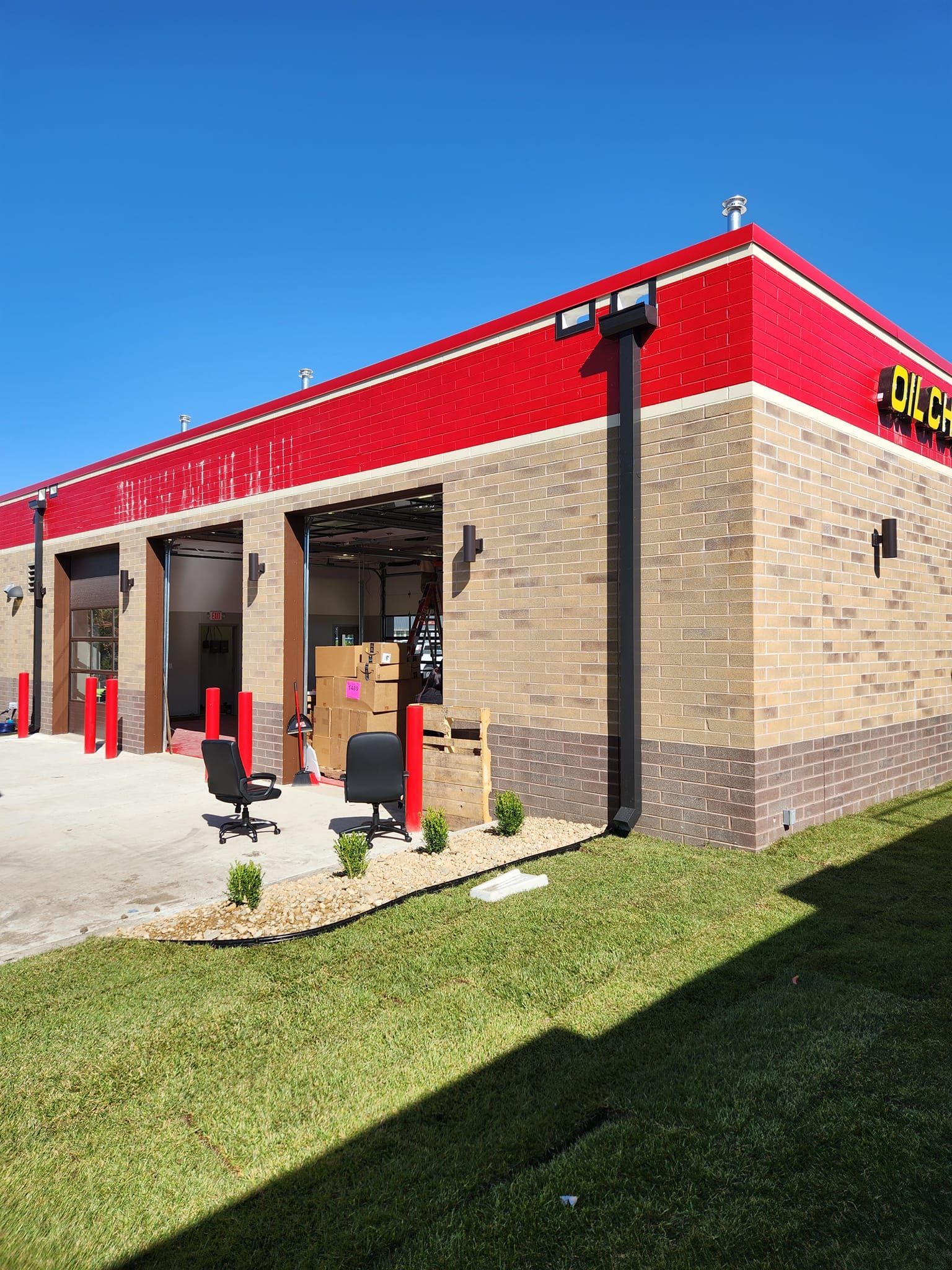 A Large Brick Building with a Red Roof is Sitting on Top of a Lush Green Field.