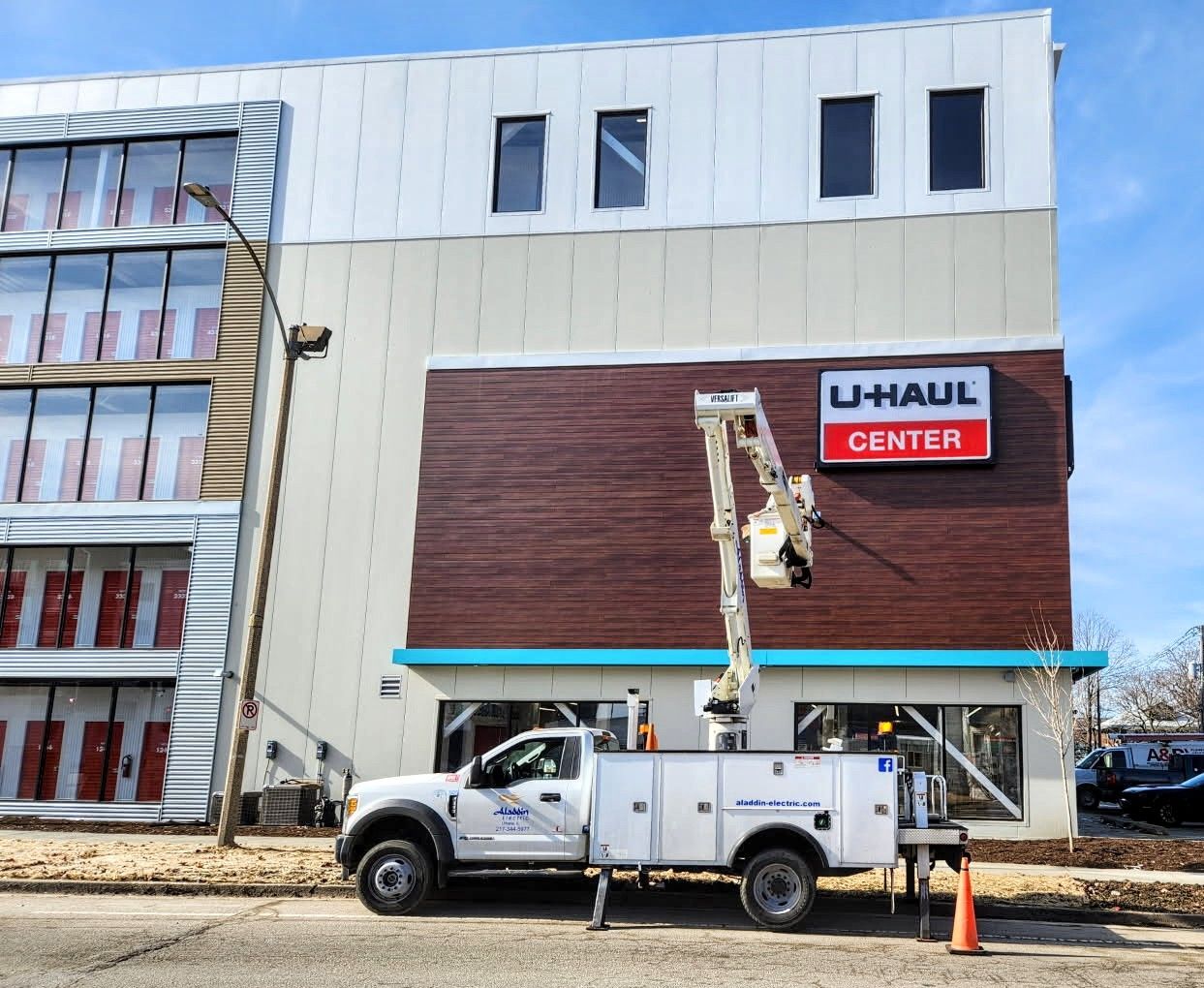U-Haul Center storefront with workers in lift trucks fixing the facade and sign