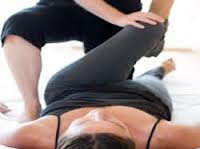 Woman on back with left knee being stretched by other person